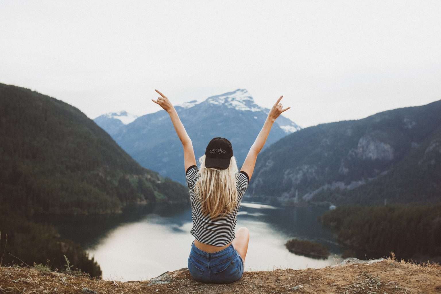 photo of a woman sat on a hill overlooking a lake