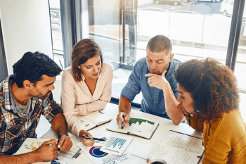 people sitting around a table looking at charts and discussing their ecommerce growth strategy