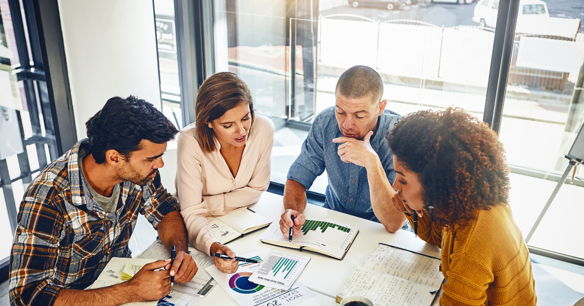 people sitting around a table looking at charts and discussing their ecommerce growth strategy