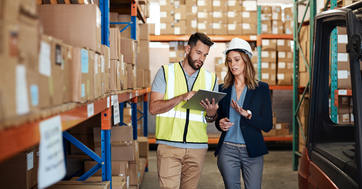 Two workers in a warehouse surrounded by stock